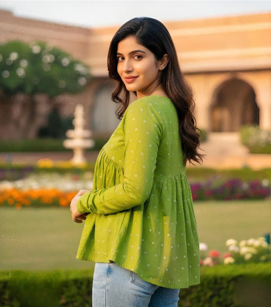 Woman in a green top standing in a garden with flowers and a building in the background