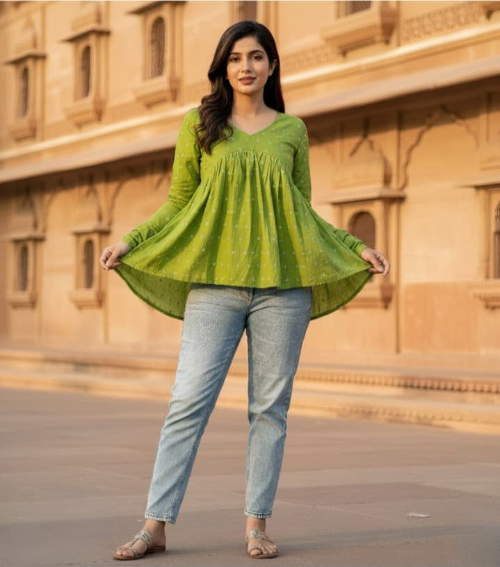 Woman wearing a green top and light blue jeans standing in front of a beige building.